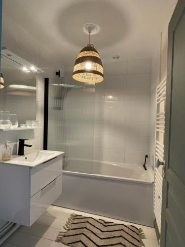 uma casa de banho com uma banheira branca, um lavatório e uma banheira tubermott em Appartement cosy et lumineux au cœur de Montreuil em Montreuil-sur-Mer