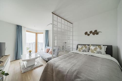 um quarto branco com uma cama grande e uma cadeira em City Sky Studio mit Balkon Vienna em Viena