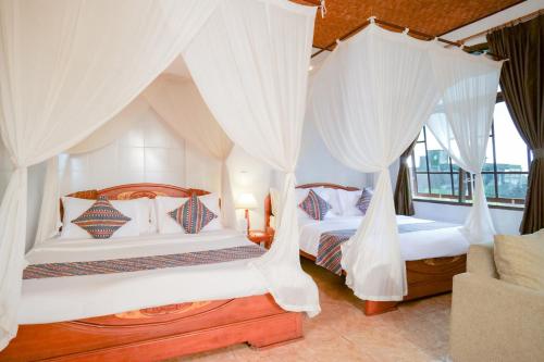 two beds in a bedroom with white drapes at Gayatri in Ubud