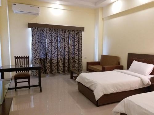 a bedroom with two beds and a desk and a chair at Hotel Sravasti Residency in Katra