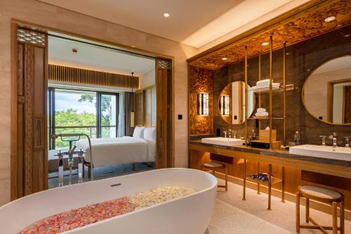 a bathroom with a tub and a bedroom at AYANA Segara Bali in Jimbaran