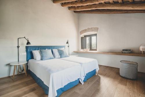 Schlafzimmer mit einem großen weißen Bett mit blauem Kopfteil in der Unterkunft Flateli Casa Oliver in Cerviá de Ter