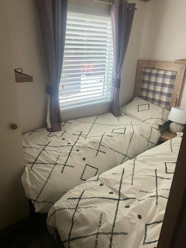 two twin beds in a room with a window at Luxury 6 Berth Caravan, Marton Mere in Blackpool
