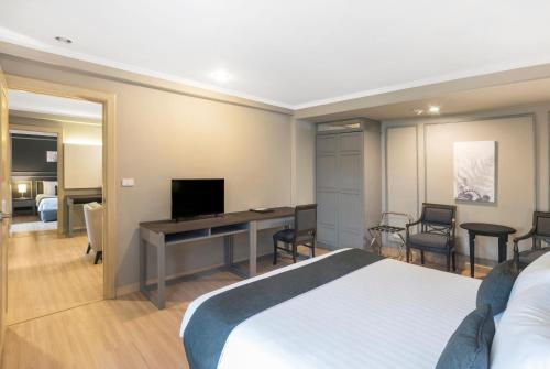 a hotel room with a bed and a desk with a television at SC Park Hotel in Bangkok