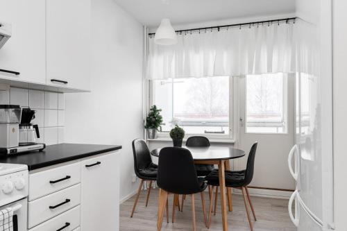a white kitchen with a table and chairs at Fresh 2BR-apartment with FREE parking in Pori