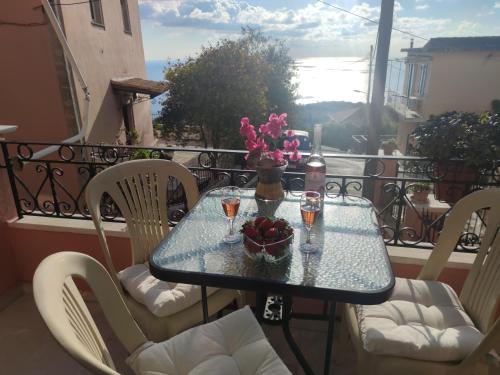 a table with a bowl of fruit and flowers on a balcony at Marios Apartment in Lákones