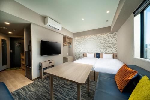 um quarto de hotel com uma cama e uma mesa e uma televisão em KOKO HOTEL Residence Asakusa Kappabashi em Tóquio