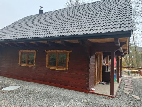 a log cabin with a black roof and two windows at Chata Peťo in Bžany
