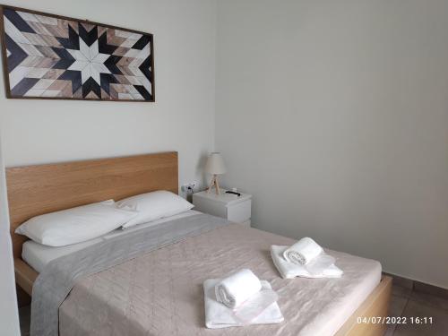 una camera da letto con un letto con due asciugamani bianchi di Smyrnis Apartments a Ermoupoli