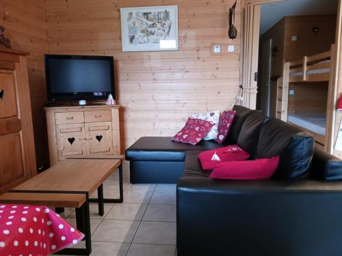 a living room with a black couch and a tv at Les fermes du Lac Gerardmer in Gérardmer