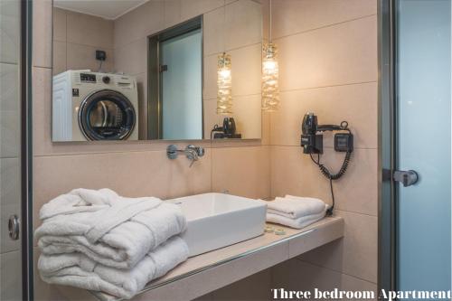Dionisos Luxury Suites في تسيليفي: حمام مع مغسلة وغسالة ملابس