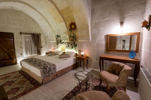 a bedroom with a bed and a table and a chair at Mesken Cave Suites in Nevsehir