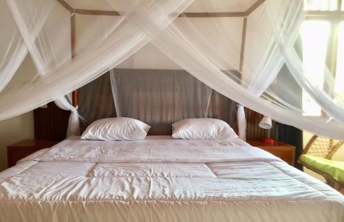 a bed with white sheets and pillows in a bedroom at Toba Sunset in Tuk Tuk