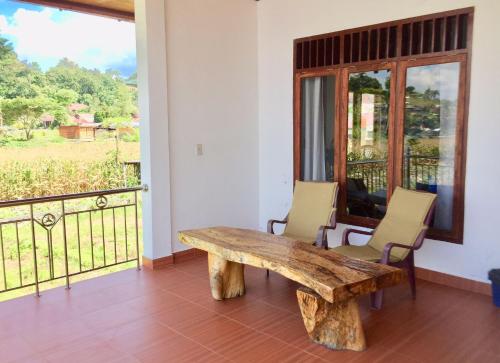 un banco de madera en una habitación con balcón en Toba Sunset en Tuk Tuk