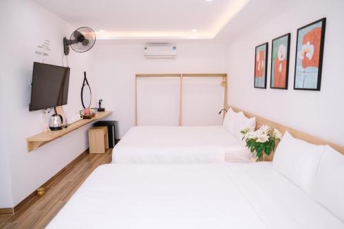 two white beds in a room with a tv at Chi's Homestay & Coffee in Hue