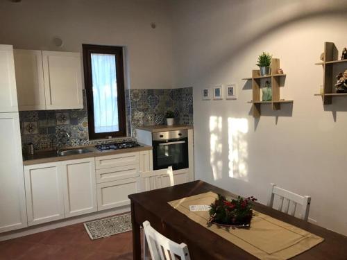 a kitchen with a table and a kitchen with a window at L'Ulivo in Villa Greco in Tindari
