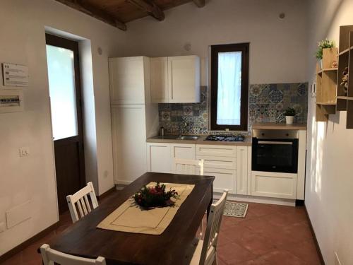 una cocina con mesa de madera y una cocina con armarios blancos. en L'Ulivo in Villa Greco, en Tindari