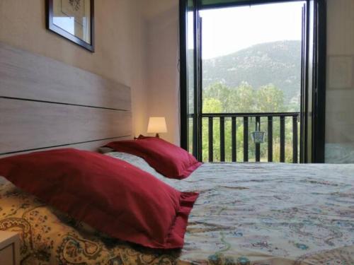 a bedroom with a bed with red pillows and a window at Apartamento con jardín y luminoso Besiberri 6 in Pla de l'Ermita