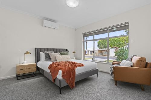 een witte slaapkamer met een bed en een stoel bij Luxury on Lewes in Perth