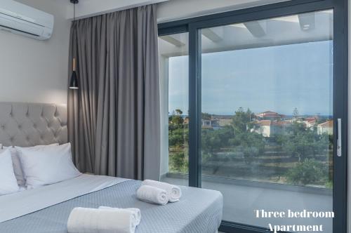 a bedroom with a bed and a large window at Dionisos Luxury Suites in Tsilivi