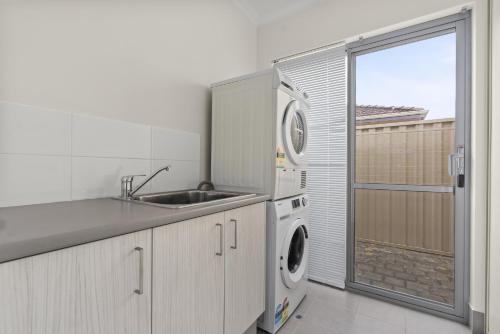 een keuken met een wastafel en een wasmachine bij Luxury on Lewes in Perth