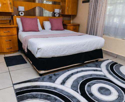 a bedroom with a large bed and a rug at Hadassa Guest House in Burgersfort