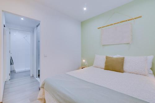 - une chambre blanche avec un grand lit blanc et des oreillers jaunes dans l'établissement Faro: Casa Trevo com terraço BBQ, à Faro