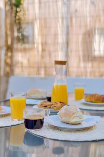 a table with plates of food and glasses of orange juice at Faro: Casa Trevo com terraço BBQ in Faro