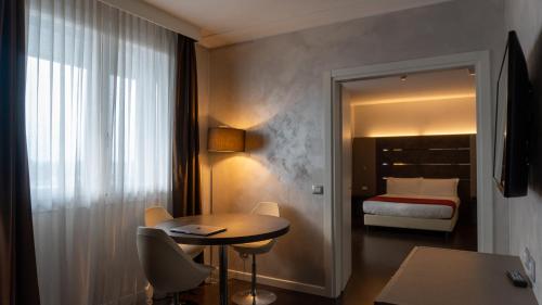 a hotel room with a bed and a table and chairs at AMEDIA Hotel in Noventa di Piave