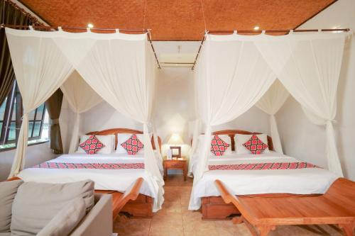 two beds in a room with white curtains at Gayatri in Ubud