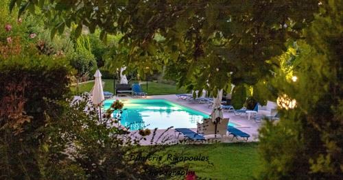 a swimming pool with chairs and umbrellas in a yard at THEA STUDIOS Eurostina in Pírgos