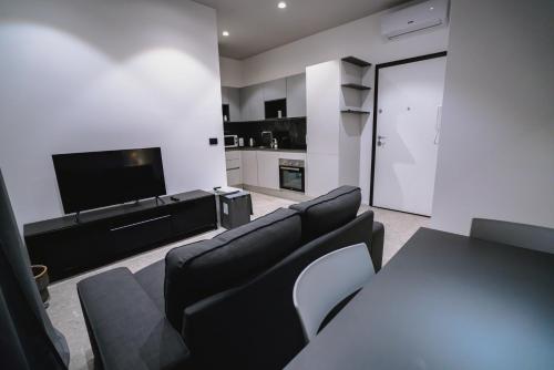 een woonkamer met zwarte lederen meubels en een flatscreen-tv bij De Luca 6 Apartments in Salerno
