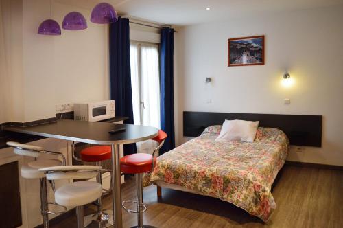 een slaapkamer met een bed en een tafel en stoelen bij Hôtel Moderne in Saint-Denis