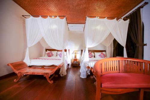 a bedroom with two beds and a red chair at Gayatri in Ubud