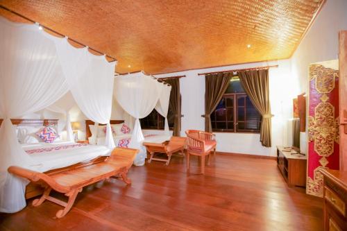 a bedroom with a bed with curtains and wooden floors at Gayatri in Ubud