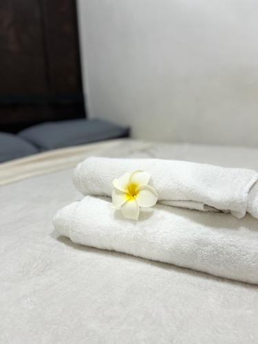 un asciugamano bianco con un fiore sopra un letto di GCASH - Taal cozy private homestay with PRIVATE attached bathroom in General Trias - Pink Room a General Trias