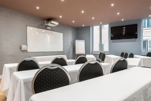 a conference room with white tables and chairs and a screen at Grand Hôtel Dauphiné Toulon, Boutique Hôtel & Suites in Toulon