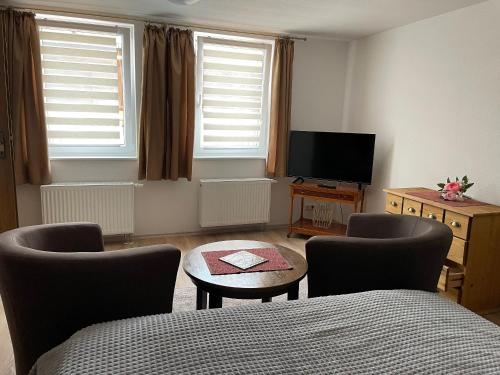 a living room with a bed and two chairs and a tv at Ferienwohnungen Clara in Arnstadt