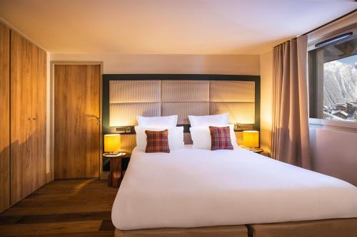 a bedroom with a large white bed and a window at Les Suites de la Potinière in Courchevel