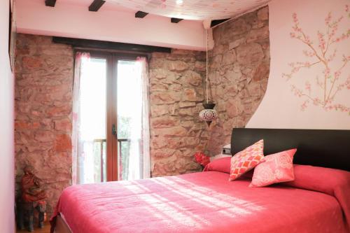 ein Schlafzimmer mit einem roten Bett und einer Steinmauer in der Unterkunft Apartamento Jaizkibel by SanSe Holidays in Lezo