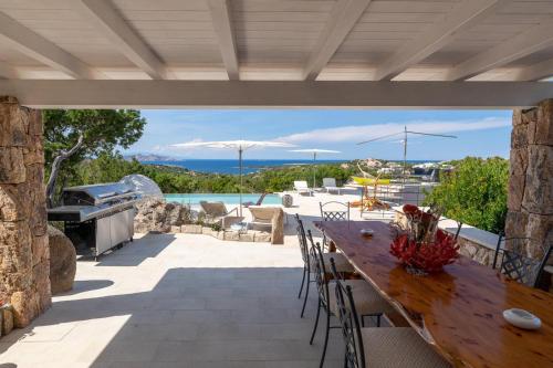 an outdoor patio with a wooden table and chairs at VILLA AMIRA Porto Cervo con vista Mozzafiato sul Mare,Piscina Privata,WELLNESS & SPA in Liscia di Vacca
