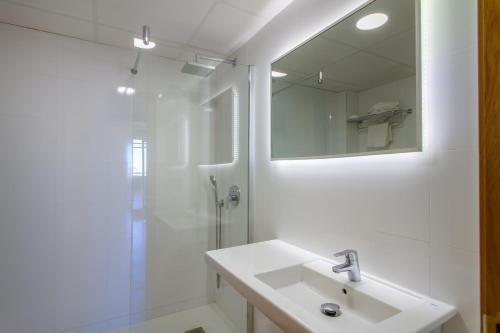 a white bathroom with a sink and a shower at Apartamentos Michel Angelo Benidorm in Benidorm
