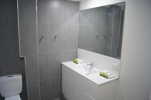 a bathroom with a toilet and a sink and a mirror at Beachside Motor Inn in Hervey Bay