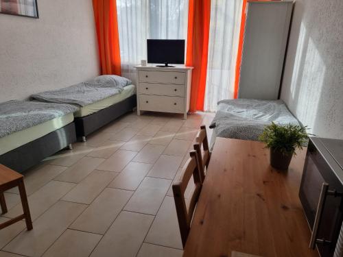 a room with two beds and a table and a tv at Workers-Sleep-Station in Cologne