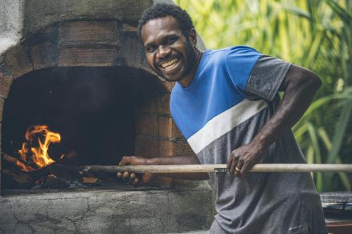 a man holding a baseball bat in front of an oven at Papaya Villa in Port Vila