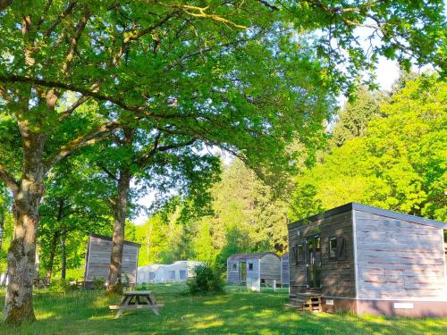 a wooden cabin in a field next to a tree at Verblijfpark Ardinam in Olloy-sur-Viroin