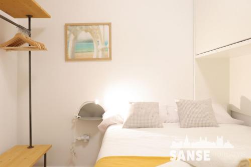 a white bedroom with a bed and a picture on the wall at Ondarreta Beach by SanSe Holidays in San Sebastián