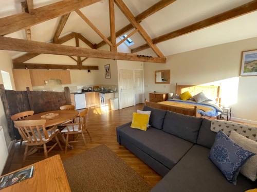 a living room with a couch and a table and a bed at The Barn Studio in Millers Dale