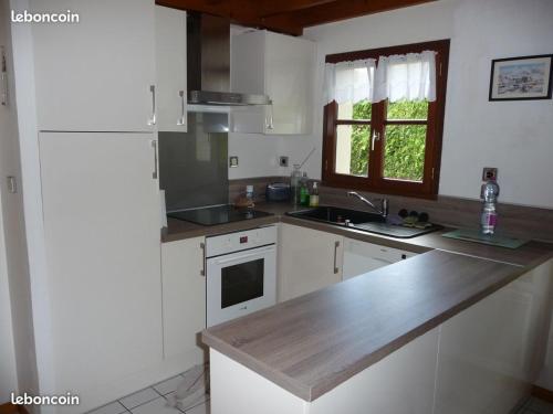 une cuisine avec des armoires blanches et un comptoir en bois dans l'établissement Maison proche centre équestre et forêt avec jardin, à Le Touquet-Paris-Plage