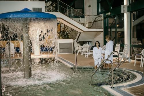 two women in white robes standing in front of a fountain at Grand Hotel Terme in Riolo Terme